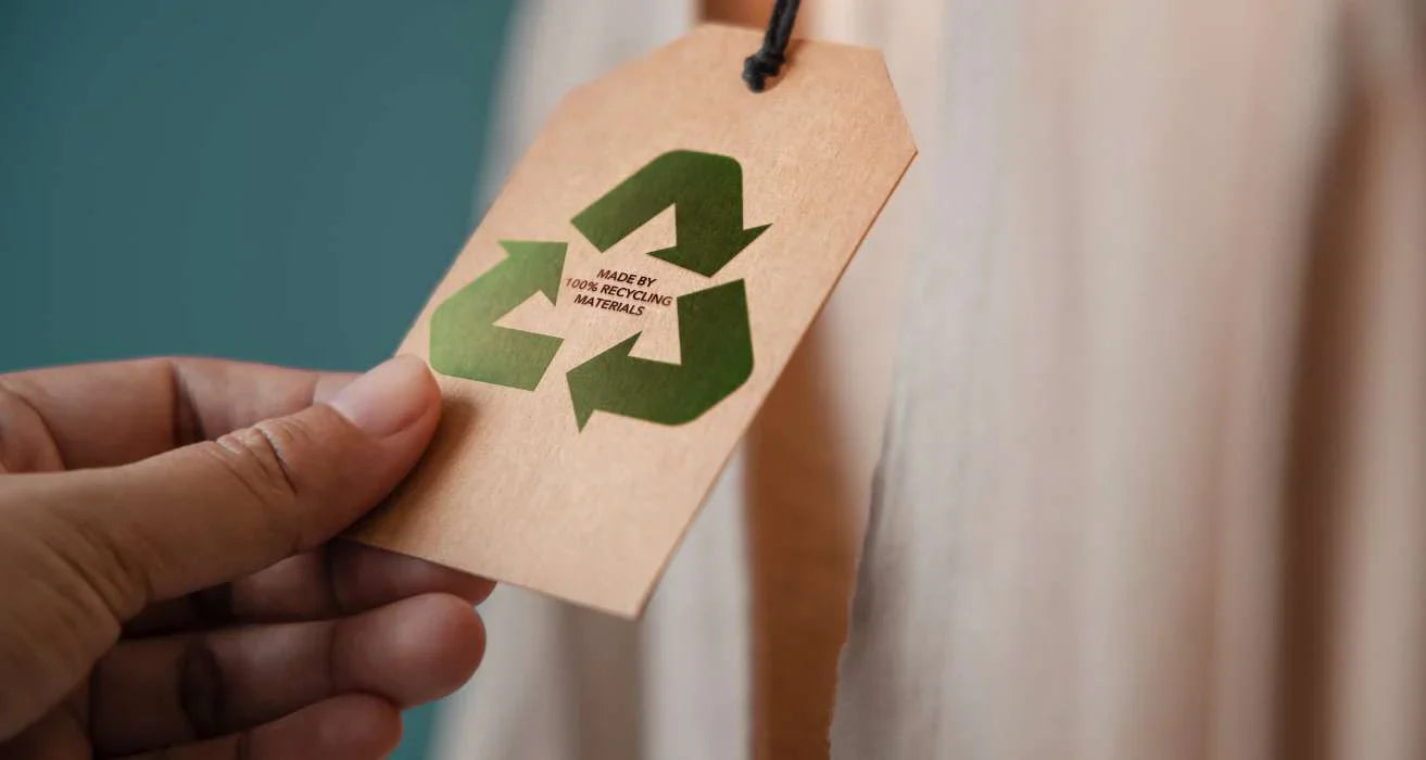 A close-up on a paper clothing tag with a generic recycling symbol, illustrating an example of corporate greenwashing.